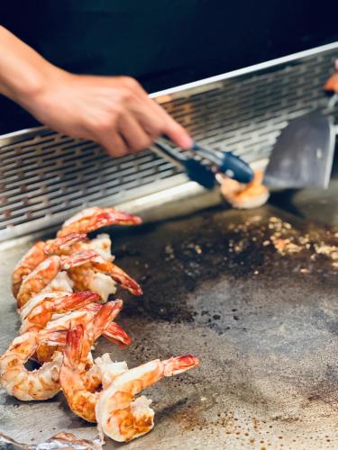 a person is cooking shrimp on a grill at Zephyr Homestay in Yanliau