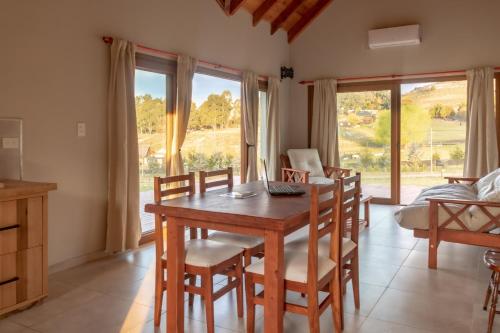 a dining room with a table and chairs and windows at Cabañas La Catalana in Tandil