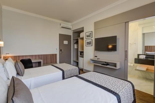 a hotel room with two beds and a flat screen tv at Slaviero Blumenau in Blumenau