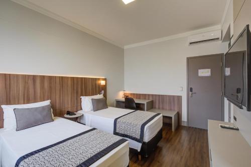 a hotel room with two beds and a tv at Slaviero Blumenau in Blumenau