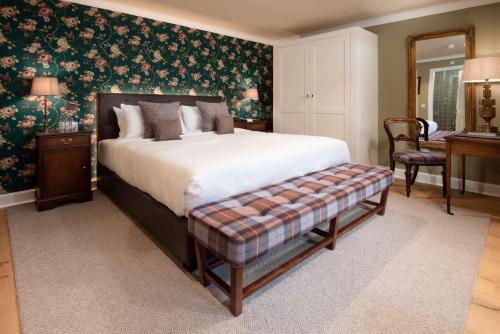 a bedroom with a large bed with a bench in it at SCHLOSS Roxburghe, part of Destination by Hyatt in Kelso