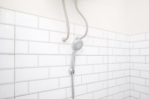 a shower with a shower head on a white tiled wall at RedDoorz Syariah near Universitas Tidar Magelang in Magelang