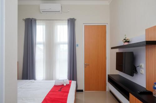 馬格朗的住宿－RedDoorz Syariah near Universitas Tidar Magelang，一间卧室设有一张床、一台电视和一个窗口。
