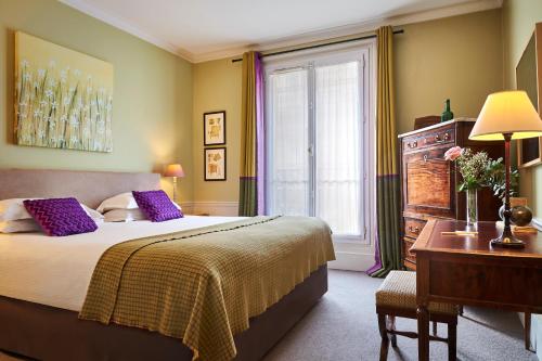um quarto com uma cama, uma secretária e uma janela em Hôtel Sainte-Beuve em Paris