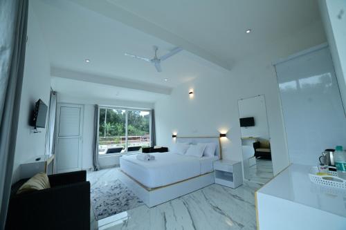 a white bedroom with a bed and a living room at RK MOUNT ORCHID coorg in Madikeri