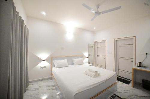 a white bedroom with a bed and a ceiling fan at RK MOUNT ORCHID coorg in Madikeri