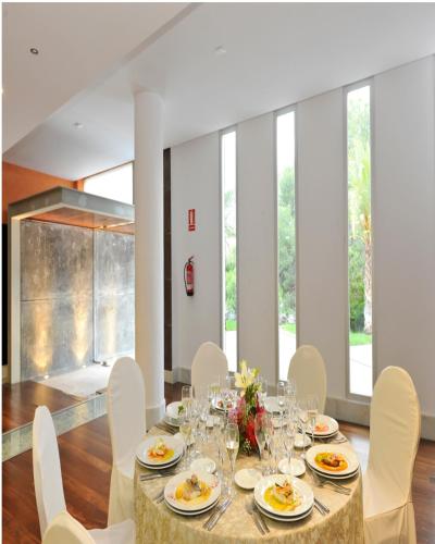 a dining room with a table and white chairs at Hotel Salobreña Suites in Salobreña