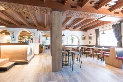 un ristorante con soffitti e tavoli in legno e sedie di Hotel Crepei a Pozza di Fassa