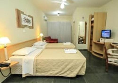 Habitación de hotel con 2 camas y TV en Bravo Suites São Carlos, en São Carlos