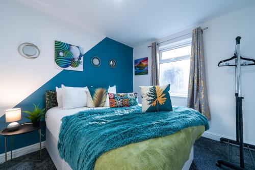 Schlafzimmer mit einem Bett mit blauer Wand in der Unterkunft Jesouth Homey 5 Bedrooms 9 Beds - Contractors - Leisure - Central Location in Hull