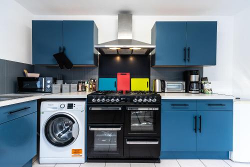a kitchen with blue cabinets and a washing machine at Jesouth Homey 5 Bedrooms 9 Beds - Contractors - Leisure - Central Location in Hull