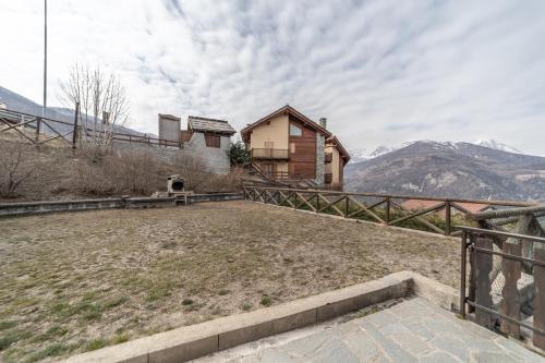a house on a hill with mountains in the background at Hotel Martin in Sauze dʼOulx
