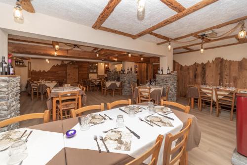 a dining room with tables and chairs and wooden ceilings at Hotel Martin in Sauze dʼOulx