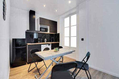 une cuisine avec une table et des chaises dans une pièce dans l'établissement Appartement 4 personnes aux Portes de Paris, à Saint-Denis