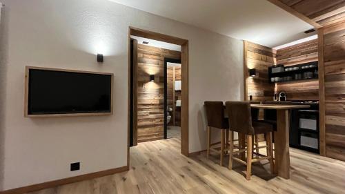a living room with a table and a television on a wall at Les Cerfs - Appartement & Studio - ANZERE in Anzère