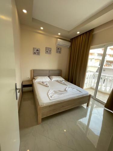 een slaapkamer met een bed en een groot raam bij Seaside Apartmens Sarande in Sarandë