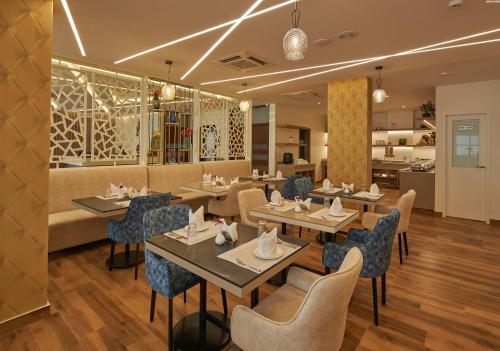 a restaurant with tables and chairs and a couch at Regenta Inn Grand-ORR, Mahadevapura in Bengaluru
