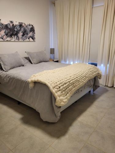 a bedroom with a large bed with a blanket on it at El Castaño Apart in Potrerillos
