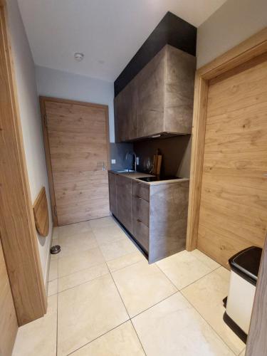 a small kitchen with wooden cabinets and a tiled floor at Auhof Wirtshaus & Suiten in Kaprun