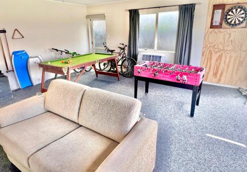 a living room with a couch and a ping pong table at Home In On Family - 400m from Papamoa Beach in Papamoa