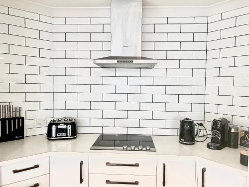 a kitchen with a stove and a white tiled wall at Home In On Family - 230m from Papamoa Beach in Papamoa