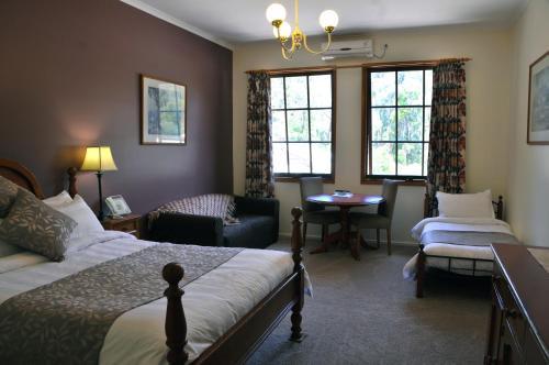 Black Spur Inn في Narbethong: غرفة نوم بسرير وكرسي وطاولة