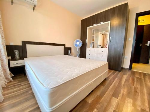a bedroom with a large white bed and a wooden floor at Green Paradise Deluxe Apartments in Primorsko