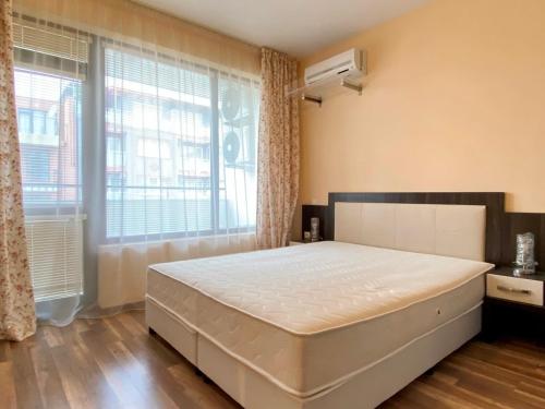 a bedroom with a large bed and a large window at Green Paradise Deluxe Apartments in Primorsko