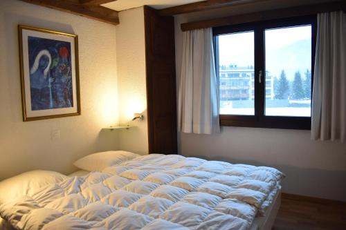 a large bed in a bedroom with a window at Parc Anemona (274 Ba) in Lenzerheide