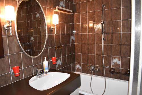 a bathroom with a sink and a mirror and a tub at Parc Anemona (274 Ba) in Lenzerheide