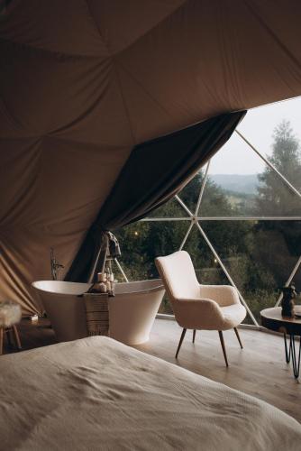 a bed and a chair and a tub in a tent at World Peaks Hotel in Richka