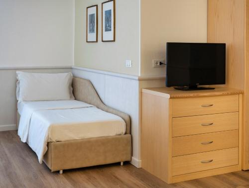 ein Schlafzimmer mit einem Bett und einem TV auf einer Kommode in der Unterkunft Arathena Rocks Hotel in Giardini-Naxos