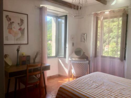 une chambre avec un lit, un bureau et une fenêtre dans l'établissement Authentique Maison de Village Corse Vue mer, à Santa-Maria-Poggio