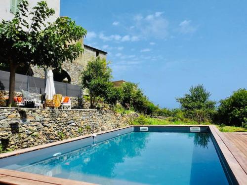 - une piscine dans une cour dotée d'un mur en pierre dans l'établissement Authentique Maison de Village Corse Vue mer, à Santa-Maria-Poggio