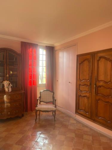een kamer met een stoel, een dressoir en een raam bij Suite le Quervalat dans magnifique bastide 18eme in Aix-en-Provence