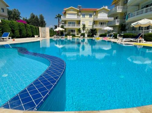 a large swimming pool with blue water in front of a building at Luxury Flat of Cleodora Residence in Serik
