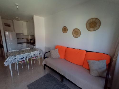 ein Wohnzimmer mit einem orangenen Sofa und einer Küche in der Unterkunft Ático con vistas a la ría de Arosa in Rianjo