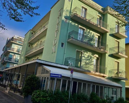 Alevon Hotel في ريميني: عماره خضراء فيها بلكونات جانبيه
