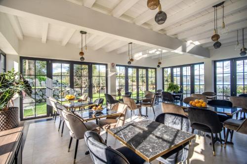 un restaurant avec des tables, des chaises et des fenêtres dans l'établissement Vigna Caio Relais & Spa, à Bracciano