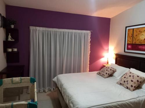 1 dormitorio con paredes moradas y 1 cama con 2 almohadas en Casa Familiar Villa Carlos Paz en Villa Carlos Paz
