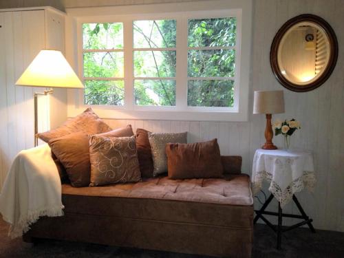 a couch with pillows in a room with a window at Devon Long Barn in Bowral