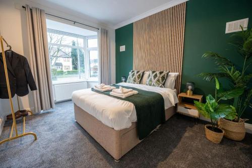 a bedroom with a large bed with green walls at Evergreen Lodge-Wyndale-4BR WParking BHam NEC in Birmingham