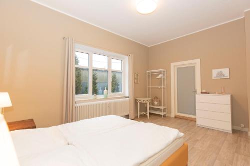 1 dormitorio con cama blanca y ventana en Alter Fischereihafen 52 en Cuxhaven