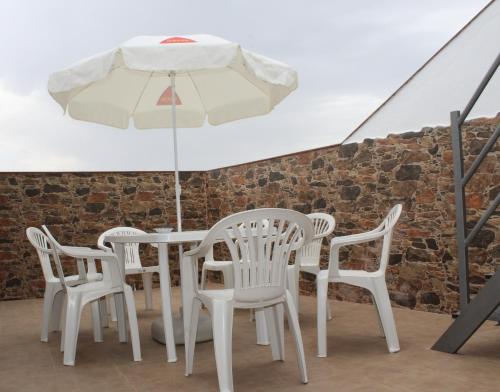 een witte tafel en stoelen en een parasol bij El Rincón de Matías (Apartamento turístico) in Segura de León