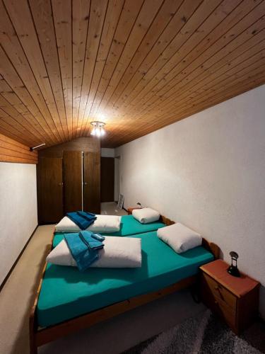 two beds in a room with a wooden ceiling at Hotel Péz Ault in Disentis