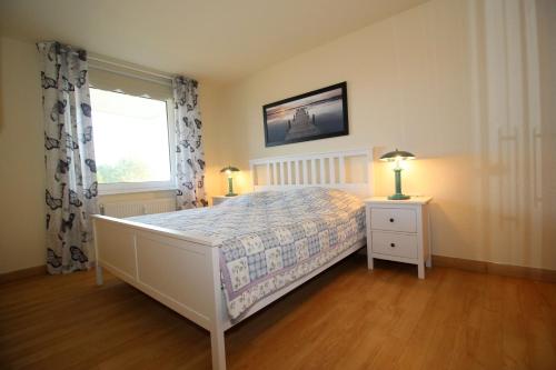 een slaapkamer met een bed, een raam en 2 lampen bij Kurpark-Residenz 108 in Döse