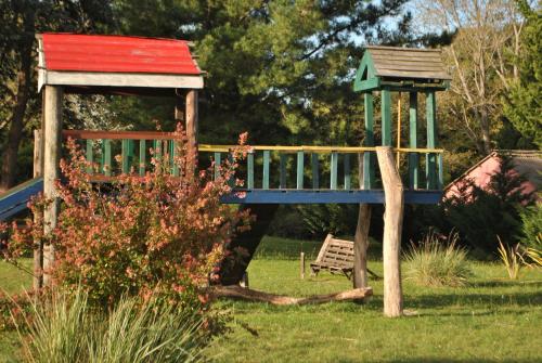 un parque infantil en un patio con techo rojo y verde en Cabañas Las Dinas en Tandil