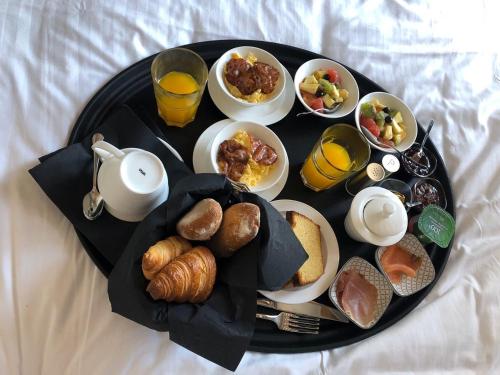 a breakfast tray with breakfast foods on a bed at Hôtel Le Chantilly in Chantilly