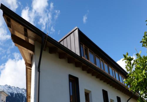 a house with a roof with mountains in the background at pradl elf my- apartment in Innsbruck