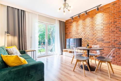 a living room with a green couch and a brick wall at Loft Apart in Iława